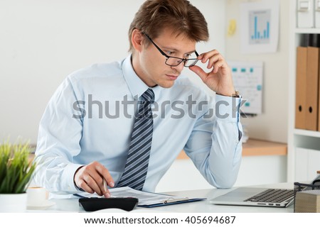 Portrait of bookkeeper or financial inspector adjusting his glasses making report, calculating or checking balance. Home finances, investment, economy, saving money or insurance concept