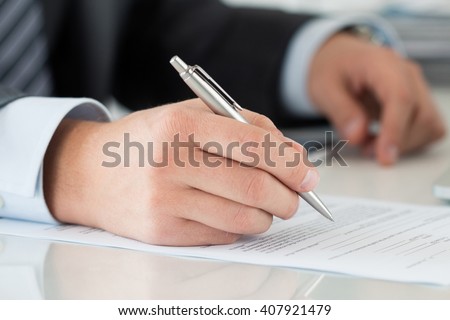 Close-up of businessman hands signing documents. Man writing something sitting at his office. Partnership agreement of contact signing, closing balance or making financial report concept