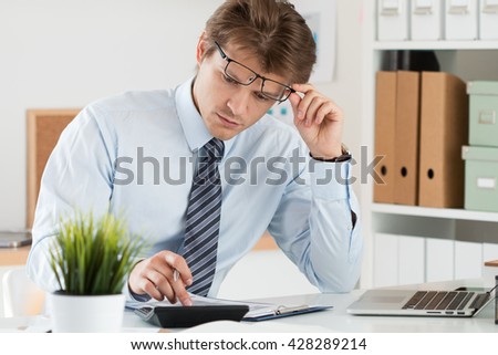 Portrait of bookkeeper or financial inspector adjusting his glasses making report, calculating or checking balance. Home finances, investment, economy, saving money or insurance concept