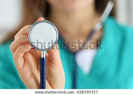 Beautiful smiling female medicine doctor holding stethoscope head ready to examine patient and help. Medical service or insurance concept. Healthcare, medical treatment, aid and patient care concept