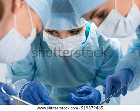 Medical team performing operation. Group of surgeon at work in operating theatre saving patient life. Resuscitation medicine team wearing protective masks saving patient. Surgery and emergency concept