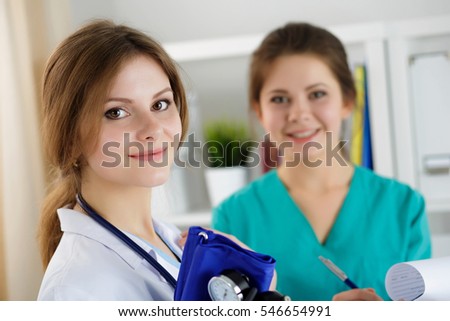 Two beautiful female medicine doctors working at their office discussing diagnose and filling patient registration or medical history form. Medical service, education, therapy and healthcare concept