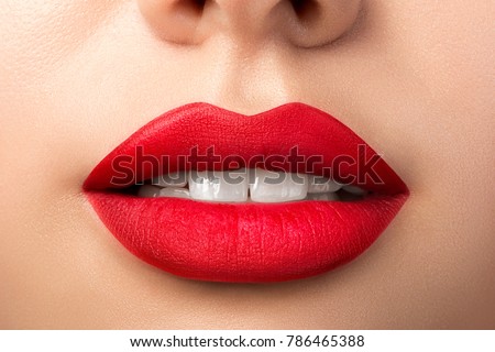 Close up view of beautiful woman lips with red matt lipstick. Open mouth with white teeth. Cosmetology, drugstore or fashion makeup concept. Beauty studio shot. Passionate kiss