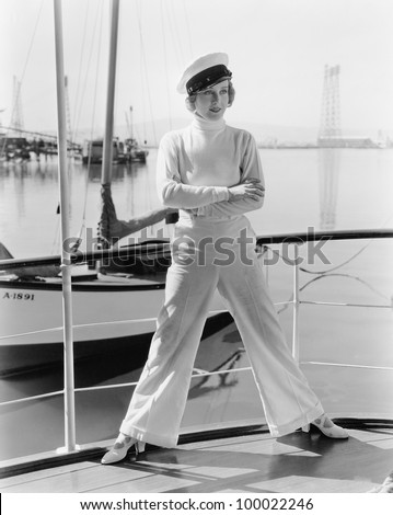 Woman in a captains hat standing on top of a sailboat