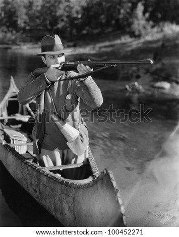 Man aiming gun from canoe