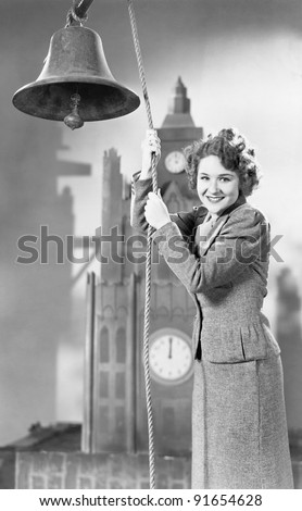 Portrait of woman ringing bell with model clock tower