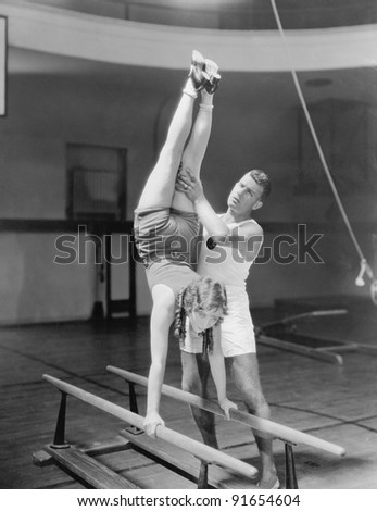 Coach helping woman on parallel bars