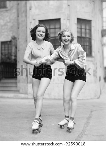 Portrait of two young women with roller blades skating on the road and smiling Portrait of two young women with roller blades skating on the road and smiling