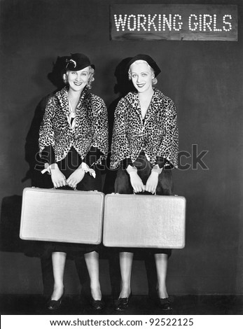Portrait of two air hostess holding suitcases and smiling