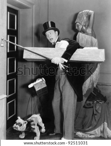 Man in formal clothing and a dog trying to ring the bell with his walking stick