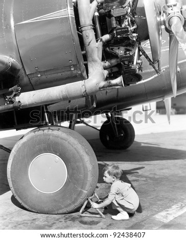 Little boy trying to fix an airplane wheel
