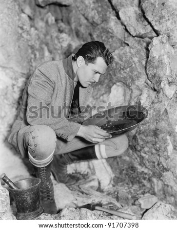 Man crouching and panning for gold