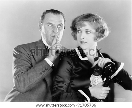 Man telling a  woman to be discrete when she is on the telephone