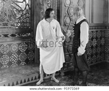 Man in a nightgown arguing with a man  in the hallway