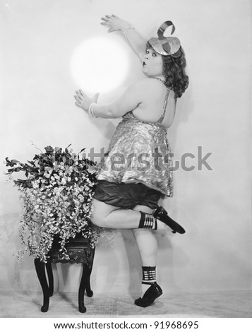 Woman pretending to hold the moon against the wall