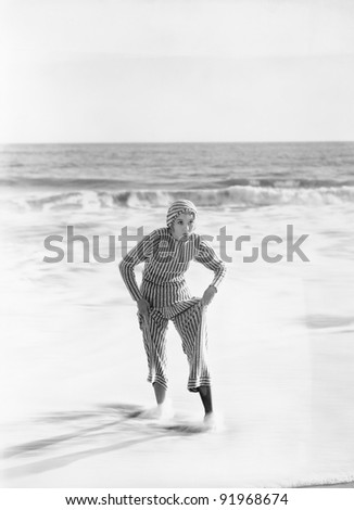 Woman in a striped suit stepping out of the ocean
