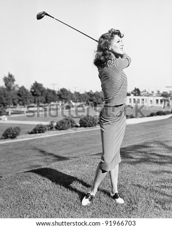 Woman on the driving range swinging a golf club