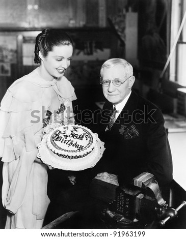 Young woman presenting a birthday cake to an elderly man