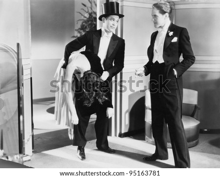 Two men in tuxedos with unconscious woman