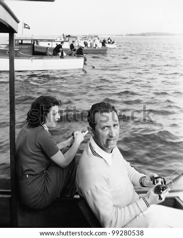Man and woman sitting on a boat on a lake with their fishing rod