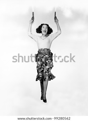 Young woman holding handguns and jumping - stock photo