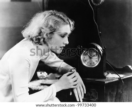 Woman setting watch to clock