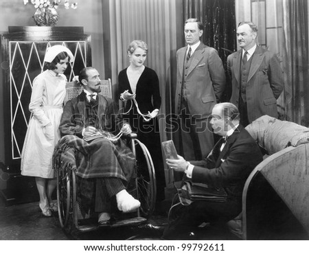 Man in a wheel chair with a broken foot and a group of people