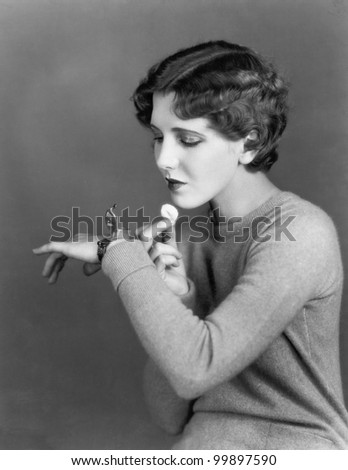 Woman using cosmetic case worn on wrist