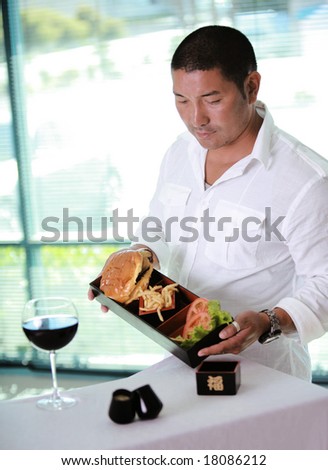 Asian Male waiter at table with hamburger