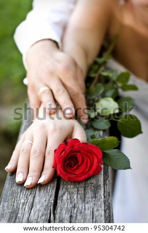 stock photo Bride and groom holding hands with wedding rings and rose