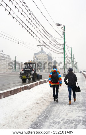 MOSCOW, RUSSIA - MARCH 15: Special car is clearing the road from snow, people walking on the street covered by snow. Extreme snowstorm in Moscow. Taken on March 15, 2013 in Moscow, Russia.