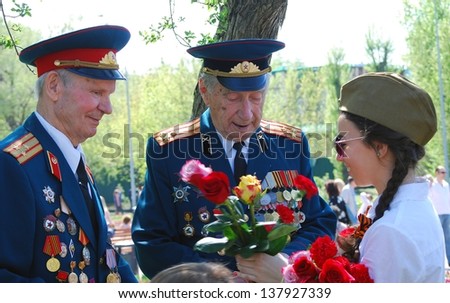 MOSCOW, RUSSIA - MAY 09: A lady gives flowers to war veterans. Victory Day celebration in the Gorky park on May 09, 2013 in Moscow.