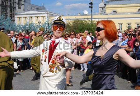 MOSCOW, RUSSIA - MAY 09: War veteran dances with a woman and young actors dressed as army soldiers on the Theater Square, by the Bolshoi Theater. Victory Day celebration on May 09, 2013 in Moscow.