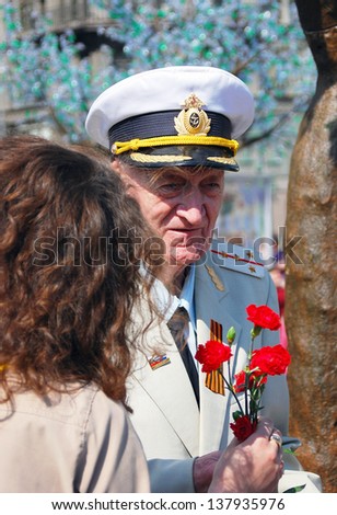MOSCOW, RUSSIA - MAY 09: A woman gives red carnation flowers to a war veteran. Victory Day celebration on May 09, 2013 in Moscow.