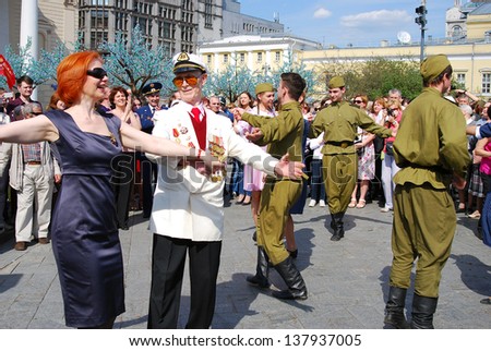 MOSCOW, RUSSIA - MAY 09: War veteran dances together with young actors dressed as army soldiers on the Theater Square, by the Bolshoi Theater. Victory Day celebration on May 09, 2013 in Moscow.