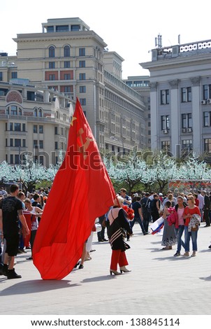 MOSCOW, RUSSIA - MAY 09: Woman walks with a red flag with hammer and sickle symbols on it. Victory Day celebration on May 09, 2013 in Moscow.