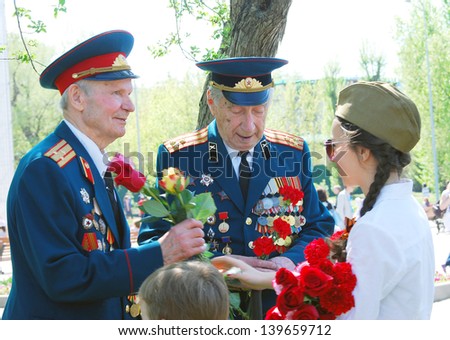 MOSCOW, RUSSIA - MAY 09: Young girl gives flowers to war veterans in the Gorky park. Victory Day celebration in the Gorky park on May 09, 2013 in Moscow.