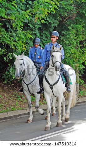 MOSCOW - JULY 20: A policeman and a police woman ride white horses on Vorobyovy mountains, a popular place for walking in Moscow. Taken on July 20, 2013 in Moscow, Russia.