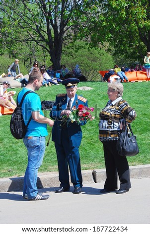 MOSCOW, RUSSIA - MAY 09, 2013: A war veteran receives flowers from a young man. Victory Day celebration in the Gorky park in Moscow.