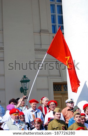 MOSCOW, RUSSIA - MAY 09, 2013: War veterans sing war songs on the Theater Square; by the Bolshoi Theater, traditional place for veterans\' meeting. Red Soviet Union flag is seen at background.