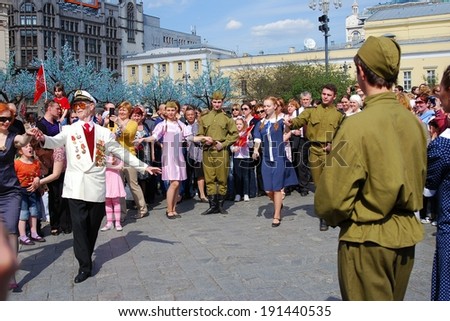 MOSCOW, RUSSIA - MAY 09: A senior war veteran in white jacket dances with a redhead woman on the Theater Square, by the Bolshoy Theater. Victory Day celebration on May 09, 2013 in Moscow.