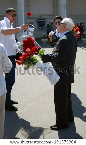 MOSCOW, RUSSIA - MAY 09: A war veteran receives a carnation flower from a young man. Victory Day celebration in the Gorky park on May 09, 2013 in Moscow.