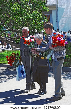 MOSCOW - MAY 09, 2014: A veteran woman walks with flowers in Gorky park. Victory Day celebration in Moscow.