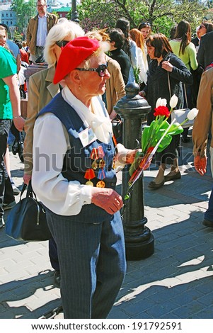 MOSCOW - MAY 09, 2014: Portrait of a war veteran woman holding flowers. Victory Day celebration in Moscow.