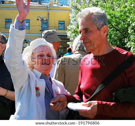 MOSCOW - MAY 09, 2014: A senior war veteran woman greets other people, she waves with his right hand. Victory Day celebration in Moscow.
