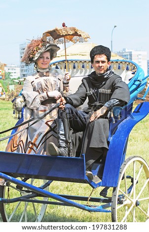 MOSCOW - JUNE 08, 2014: Portrait of man and woman in historical costumes. They sit in a carriage, a woman holds umbrella. Times and Ages International Historical Festival in Kolomenskoye park, Moscow.