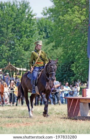 MOSCOW - JUNE 08, 2014: Horse riders competition. A woman rider is dressed in vintage military uniform. Times and Ages International Historical Festival in Kolomenskoye, Moscow.