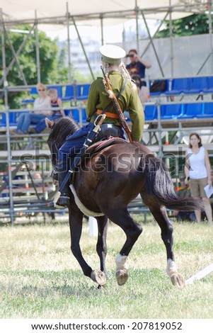 MOSCOW - JUNE 08, 2014: A horse runs away. Horse riders competition. A rider is a young woman dressed in vintage uniform. Times and Ages International Historical Festival in Kolomenskoye, Moscow.