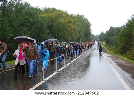 MOSCOW REGION - SEPTEMBER 02, 2012: People walk under umbrellas on the wet road. A policeman stands on the right side of the road. They walk to see Borodino living history reenactment.