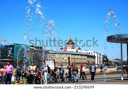 MOSCOW - MAY 09, 2014: Many people walk in Moscow city center by the Moscow river embankment. View of the Christ the Savior church, a popular touristic landmark. Blue sky background.